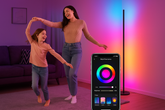 Woman and child dancing in a room with a colorful light strip and smartphone displaying app controls.